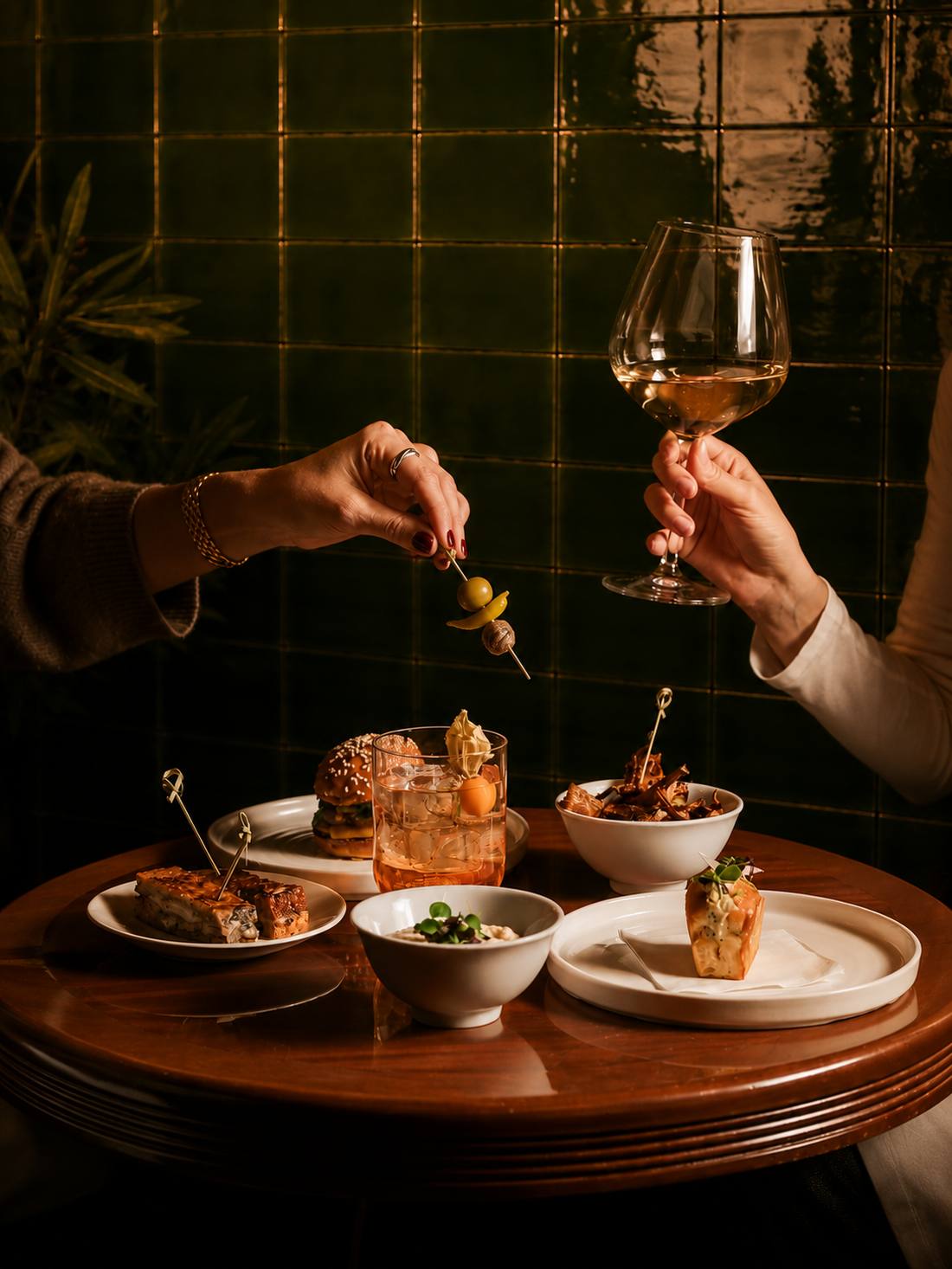 Dos personas brindando con vino y aperitivos sobre una mesa de madera