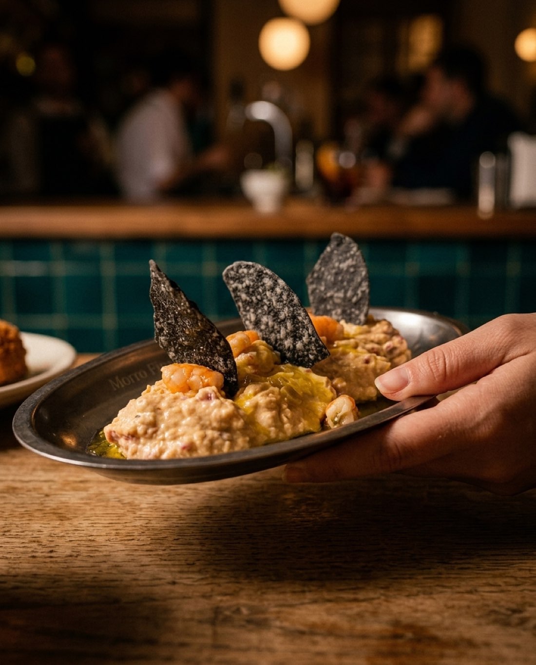 Ensaladilla de langostinos al ajillo con nachos negros, en bandeja de metal