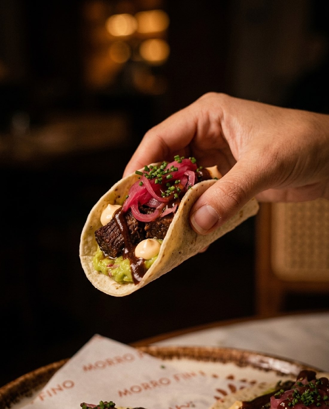 Taco de chicharrón de atún con cebolla encurtida y guacamole, servido en mano